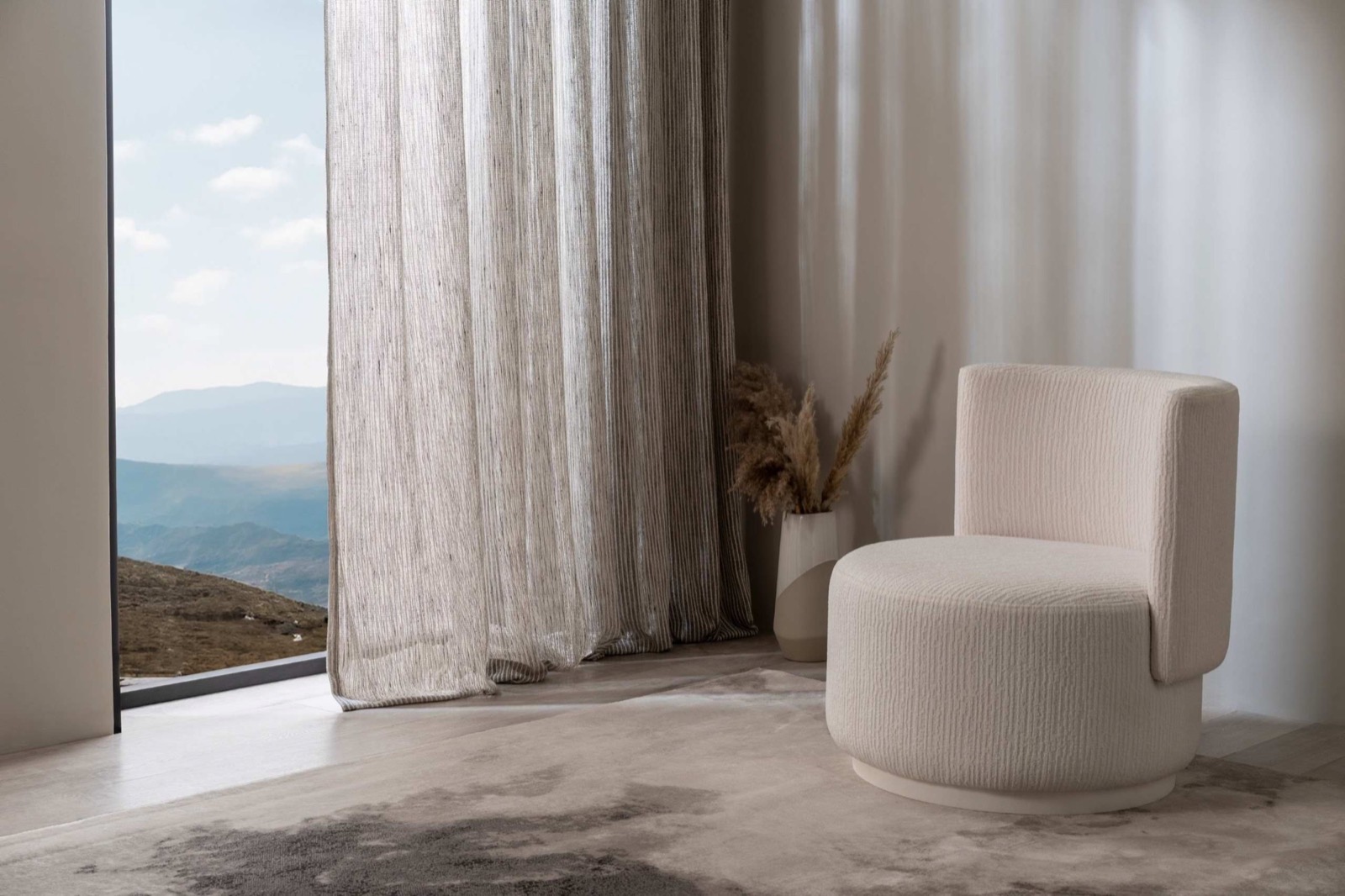 Textured sheer curtains beside a sculptural chair