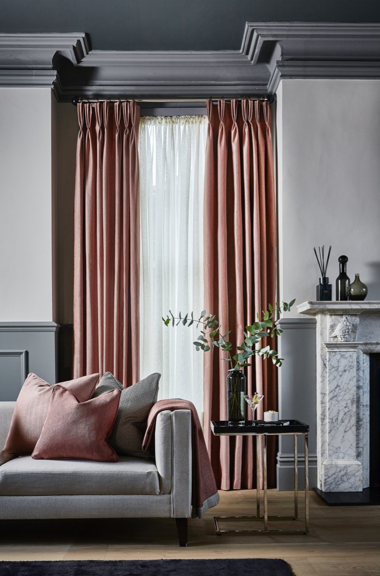 Tailored pink curtains and coordinated cushions in a refined trade interior